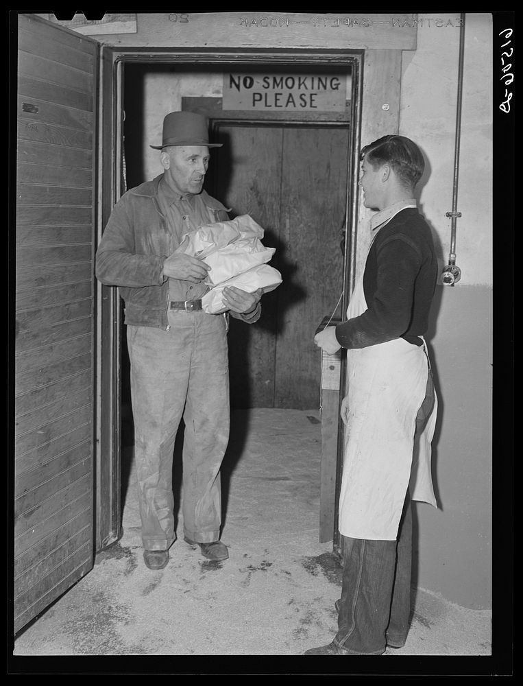 Farmer coming out of cold storage lockers with meat to take home. North Dakota. Sourced from the Library of Congress.