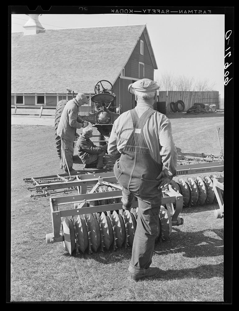 Fred Coulter, Iowa corn farmer, watching hired men adjust harrow onto tractor. Grundy County, Iowa. Sourced from the Library…