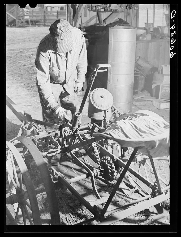 Oiling corn planter in machine shed before beginning planting operations. Grundy County, Iowa. Sourced from the Library of…