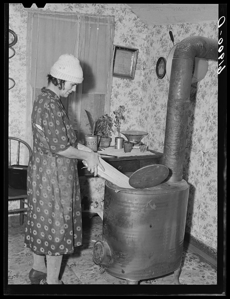 Wife of day laborer putting wood in stove. Scioto Marshes, Hardin County, Ohio. Sourced from the Library of Congress.