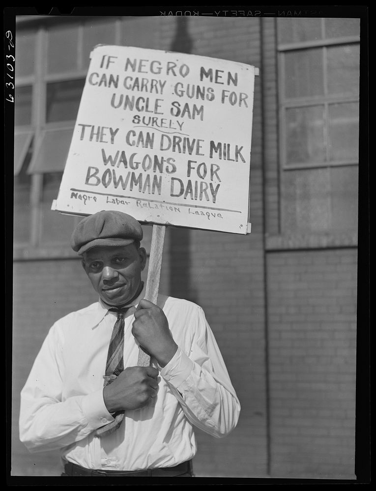  carrying sign in front of milk company. Chicago, Illinois. Sourced from the Library of Congress.