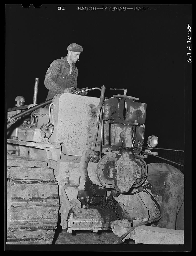 [Untitled photo, possibly related to: Member of road construction gang greasing "cats" at night. Grant County, Wisconsin].…