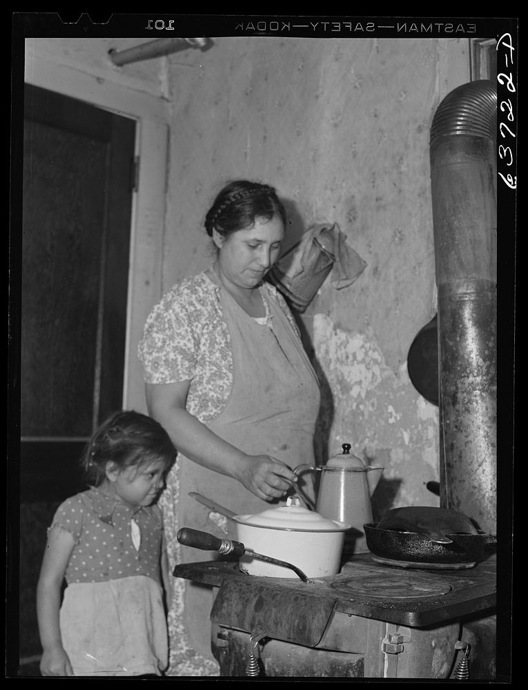 Wife and child of Mexican sugar beet worker in community kitchen, in one of the houses at Saginaw Farms, a FSA (Farm…