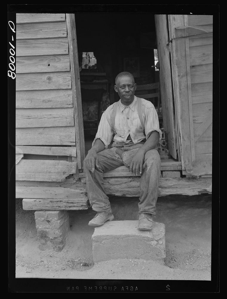 FSA (Farm Security Administration) borrower resting in the doorway of his one-room house. He lives here with two sons and a…