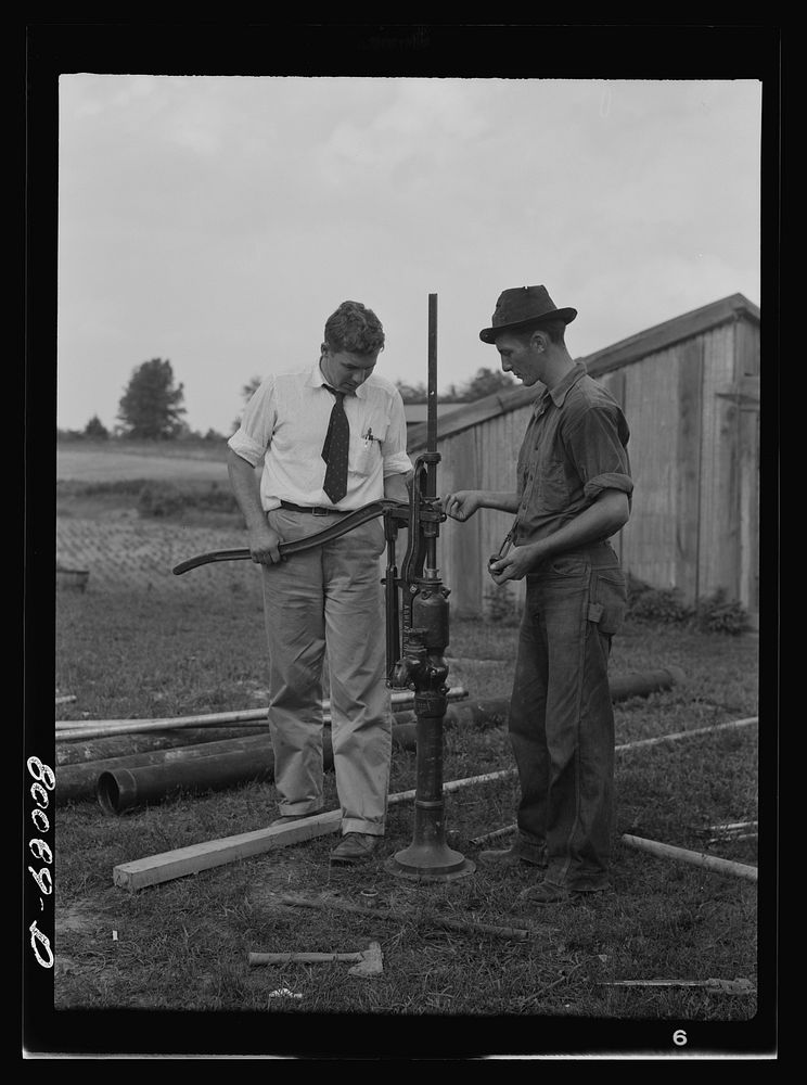 Adjusting the hand pump. Safe well demonstration near La Plata, Maryland. Charles County. Sourced from the Library of…