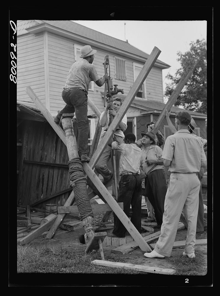 Pump is lowered on pump rod and casing before settling drop pipe in place. Long well project, Saint Mary's County, Maryland.…