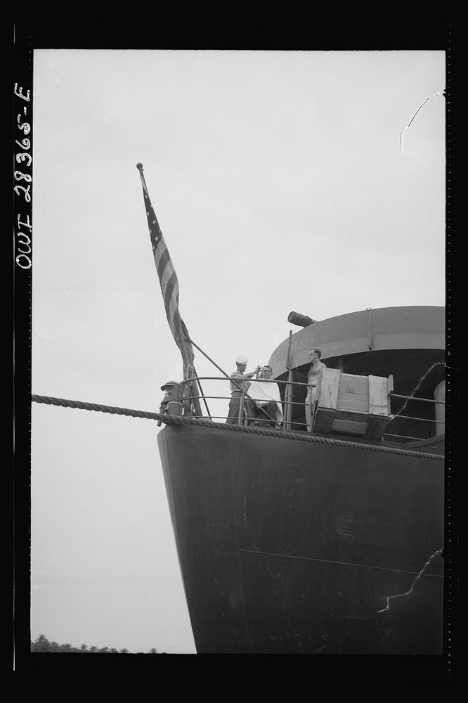 American seaman giving a haircut to a fellow member of the crew as they pull in to unload their freight which is destined…