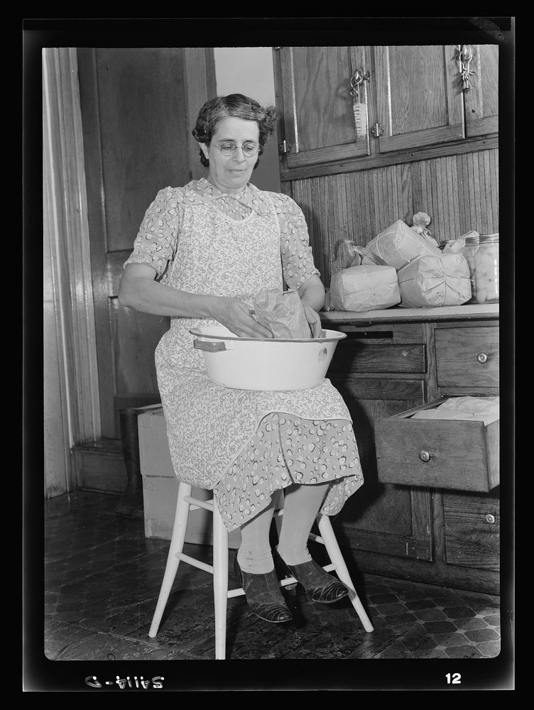 [Mrs. Albert Yaeger] storing home-dried [apples or corn] in sugar sacks. Sourced from the Library of Congress.