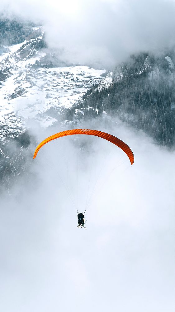 Adventure phone wallpaper background, Paragliding on a cloudy day through the mountain