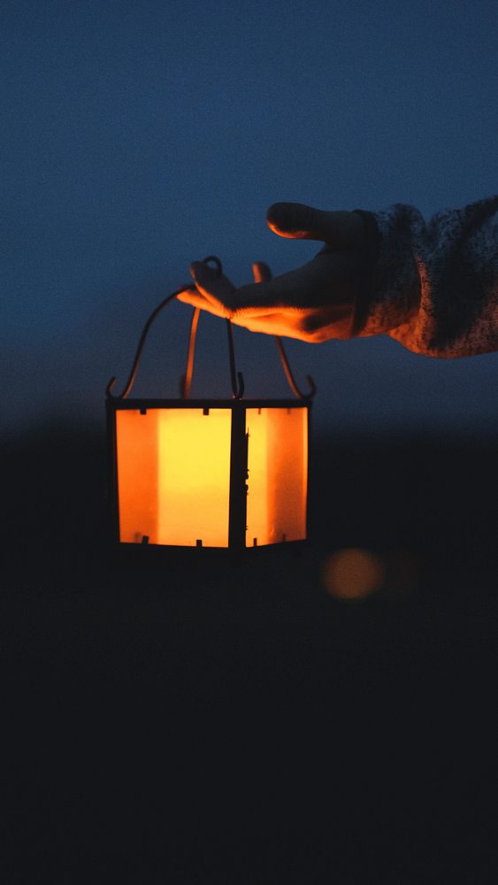 Phone wallpaper background, hand holding a lantern in the dark