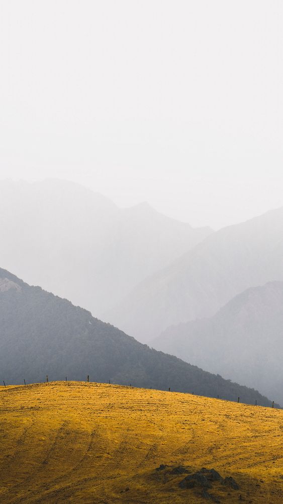 Nature phone wallpaper background, grassland among misty mountains landscape