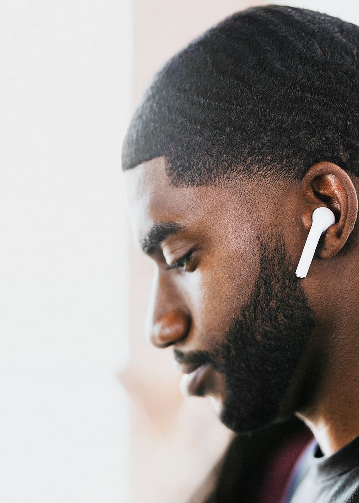 African American man listening to music on wireless earphones