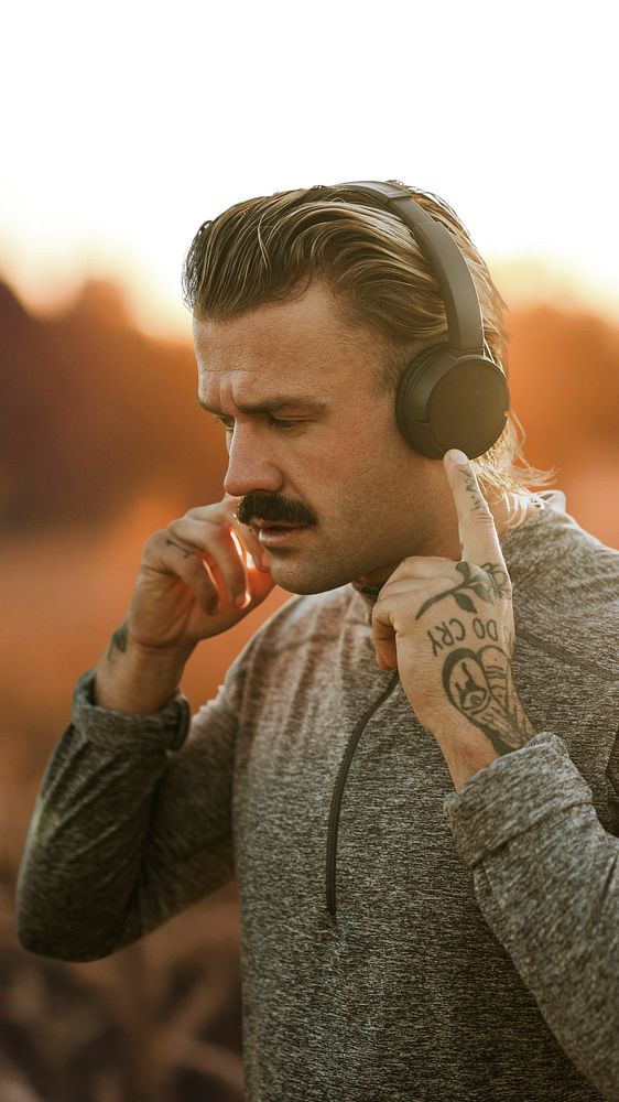 Handsome man wearing wireless headphones in the countryside remixed media