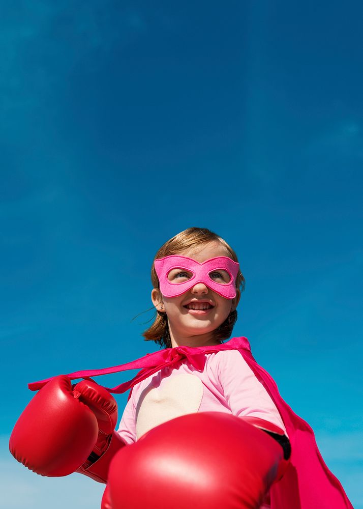 Superhero girl smiling on blue sky for education portrait