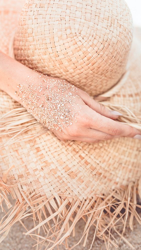 Mobile phone wallpaper, beach sandy hand touch a straw hat warm tone filter