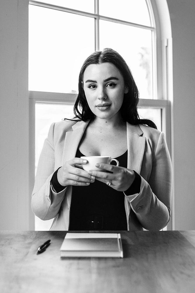 Businesswoman drinking coffee in a meeting room, black and white photo