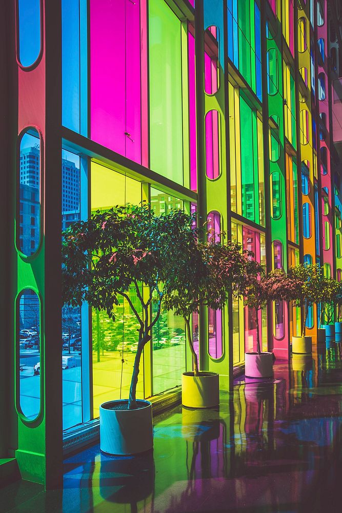 Multicolored rainbow glass windows with potted trees in front in urban street. Original public domain image from Wikimedia…