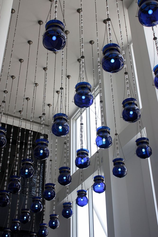 Blue lanterns hanging from the ceiling in a white tall room. Original public domain image from Wikimedia Commons