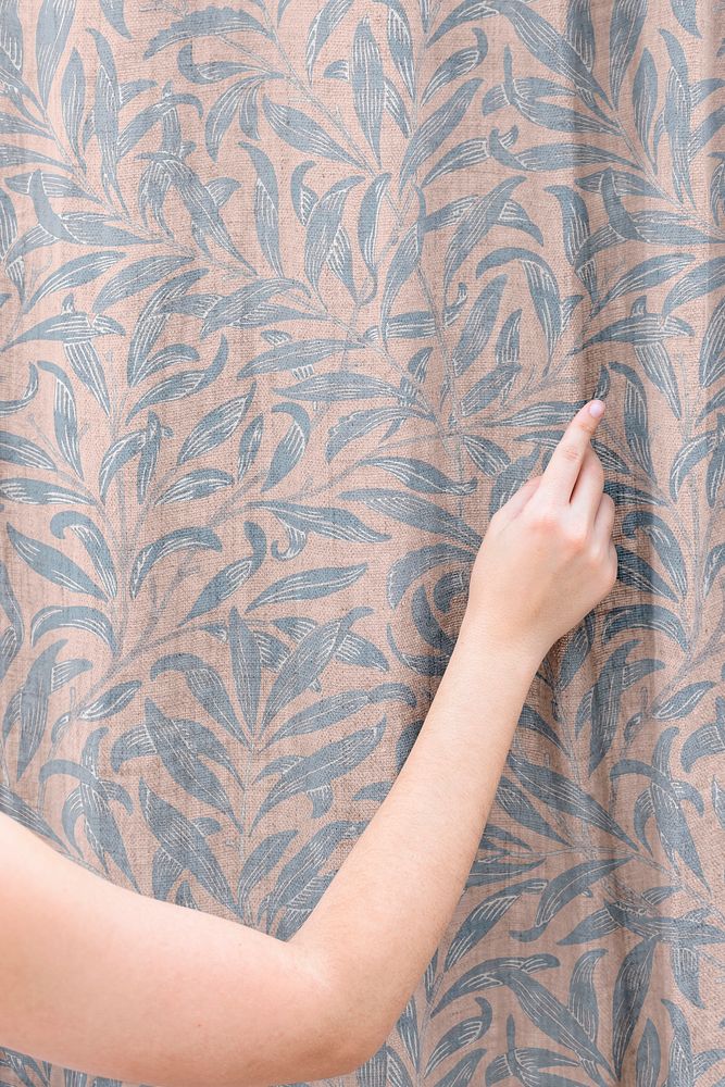 Woman closing a William Morris curtain in a living room