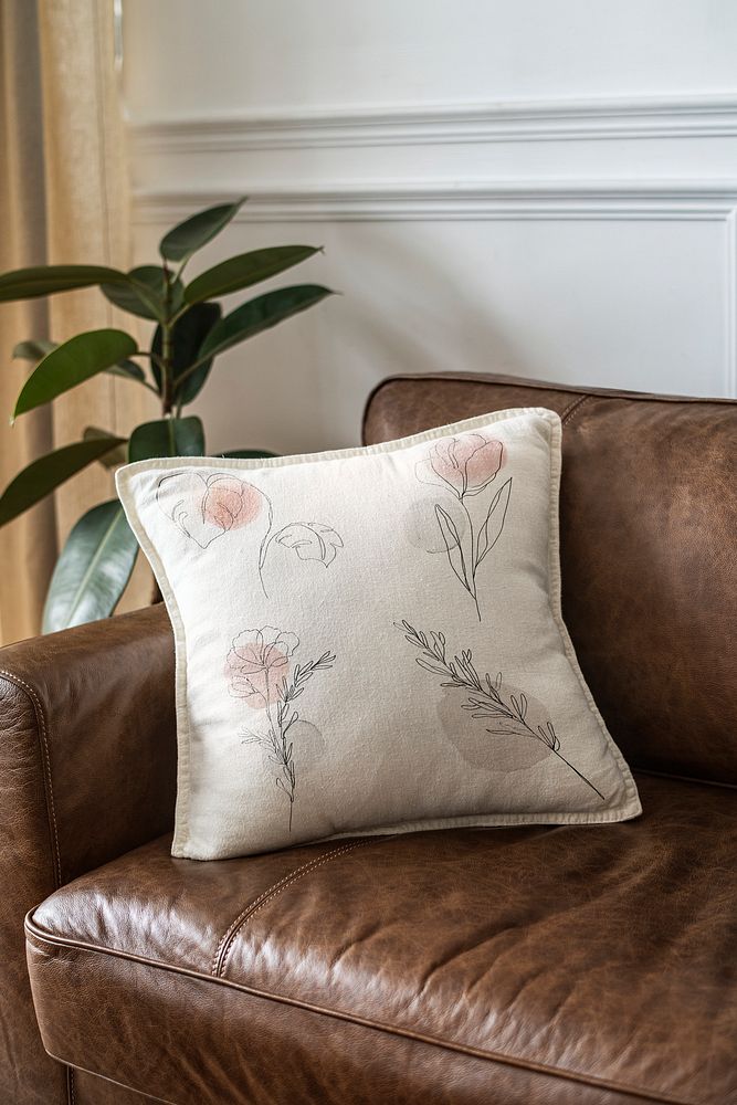Cushion with minimal floral line art on a leather couch