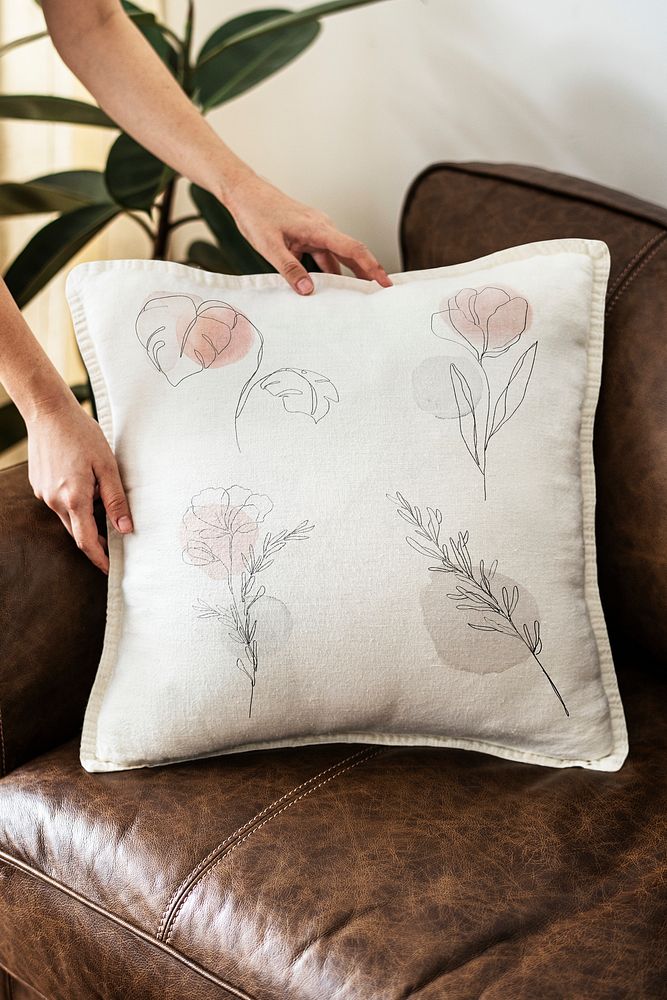 Cushion with minimal floral line art on a leather couch