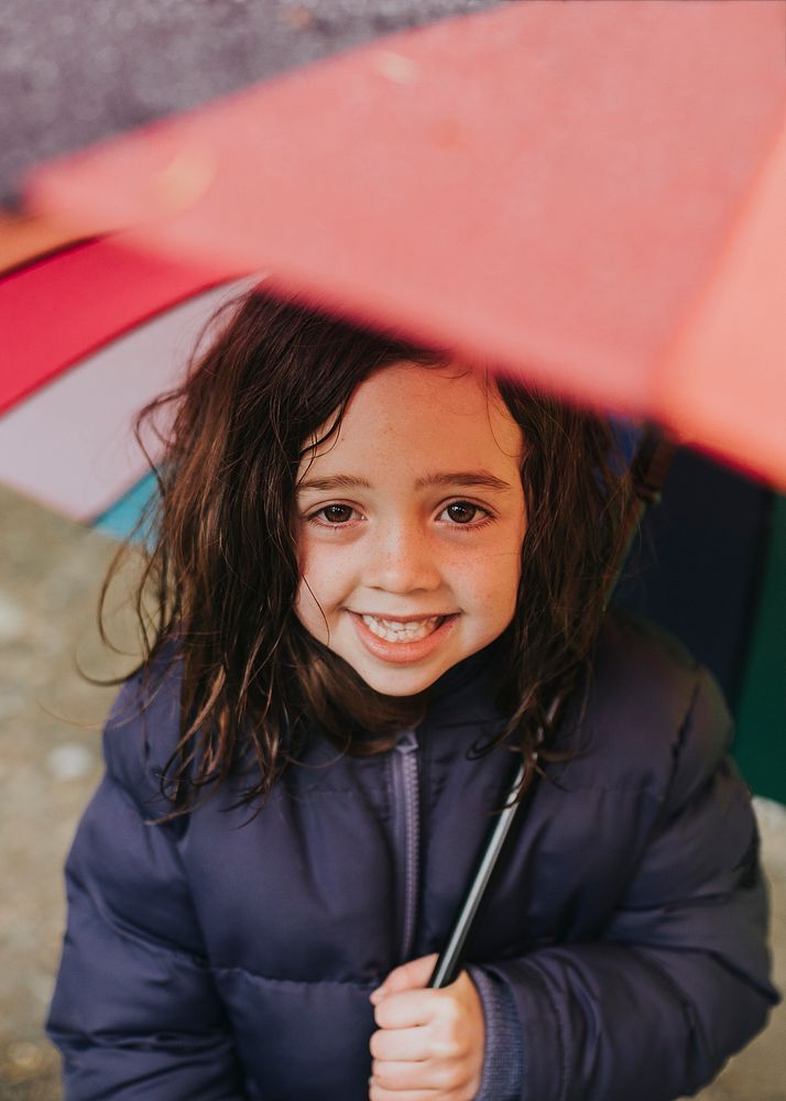 Little girl smiling with an umbrella while on a family trip outdoors portrait