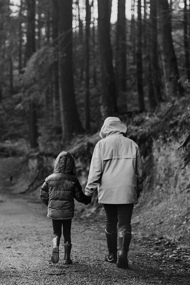 Mother walking with her daughter in the forest rear view black and white