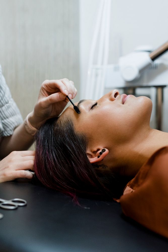 Beautician giving eyebrow treatment to a customer at a beauty salon