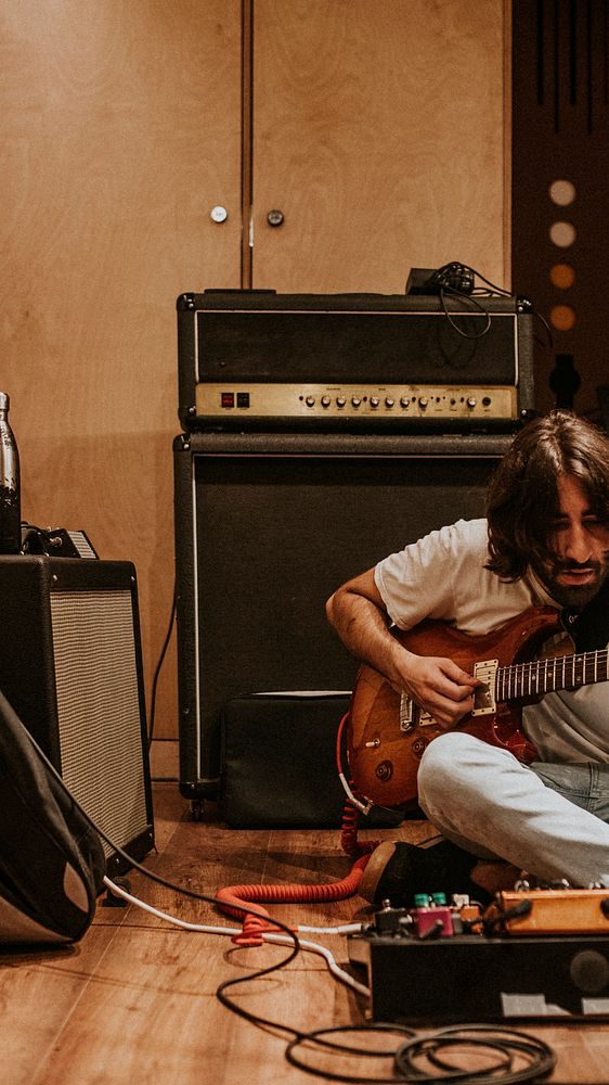 Guitarist playing rock music, studio recoding, sitting on the floor
