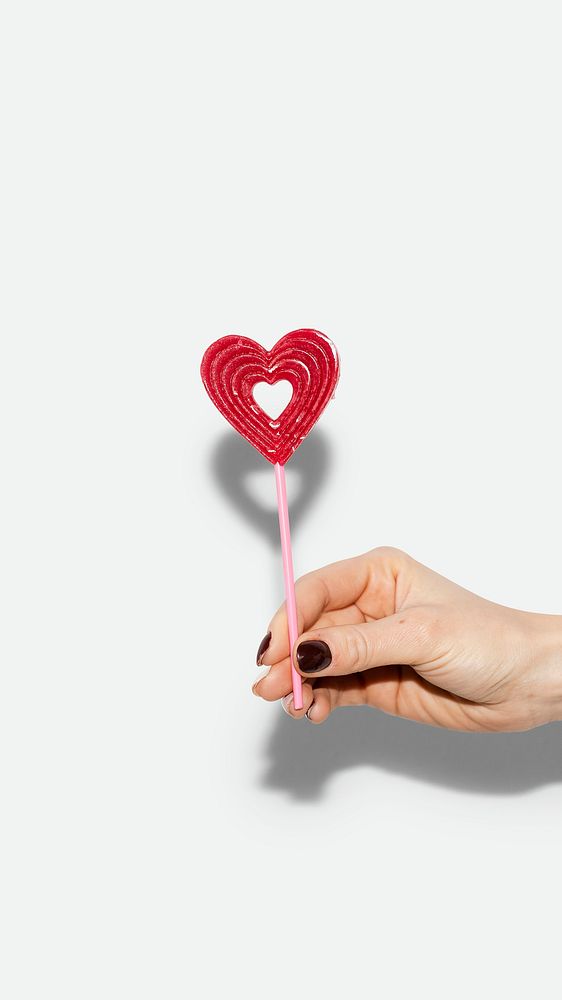 Valentine phone wallpaper, love mobile background, hand holding heart lollipop