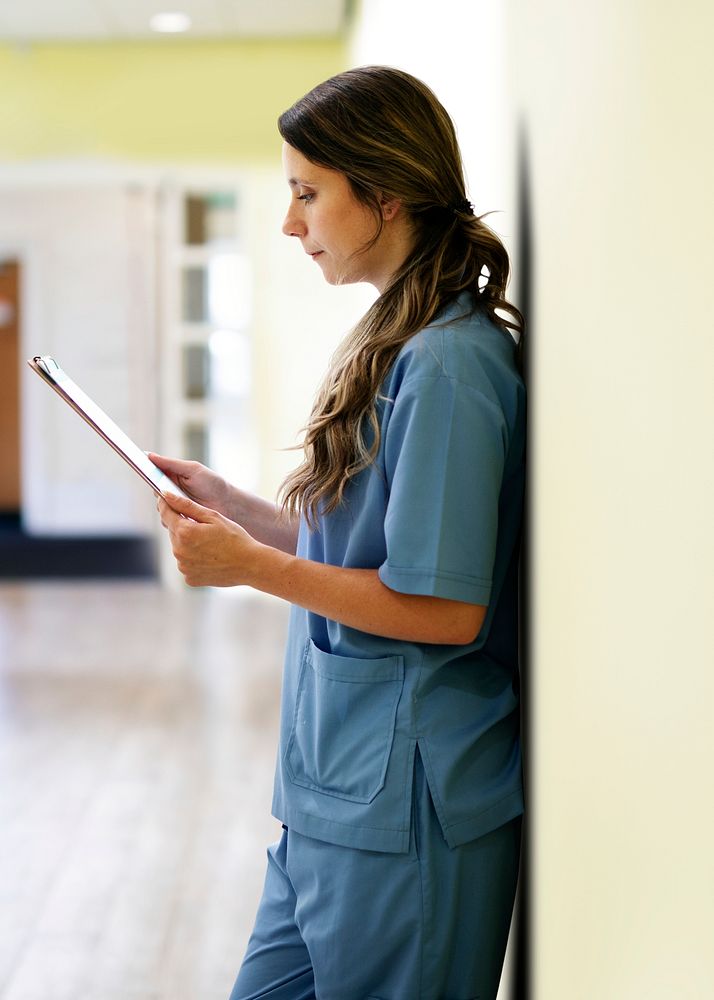 Nurse reading patients record in hallway