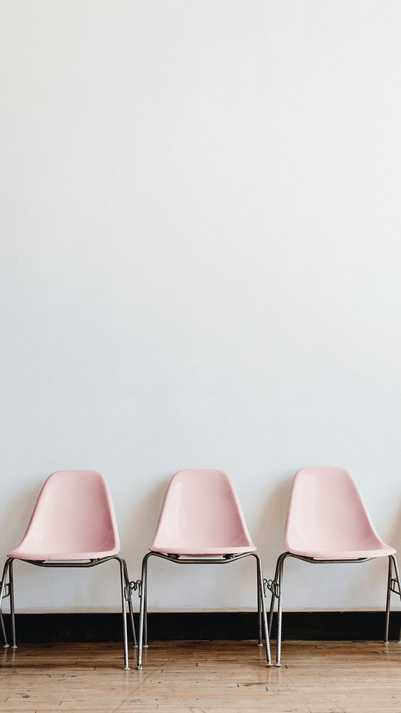 Three empty pastel pink chairs in a room