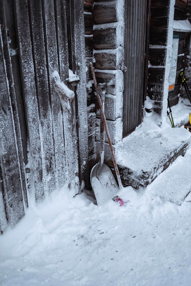 Frosty snow shovel by a wooden wall
