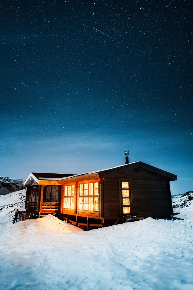 Lights from a wooden cabin in the remote wilderness of Greenland