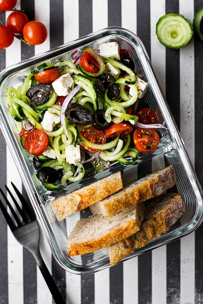 Greek salad with bread in a glass container