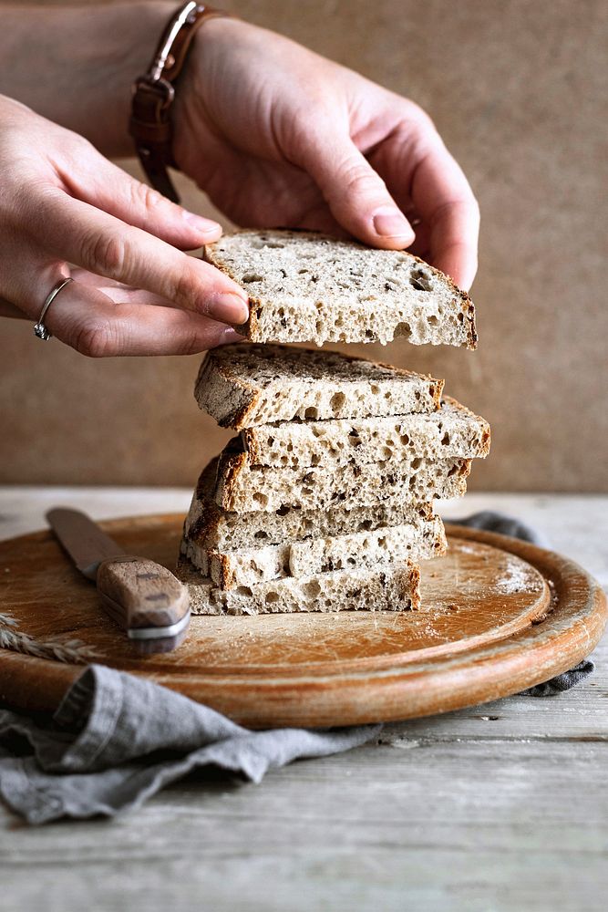 Sliced bread stacked on a wooden cutting board