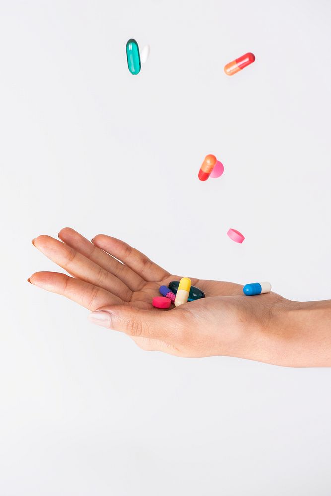 Colorful pills falling to a palm