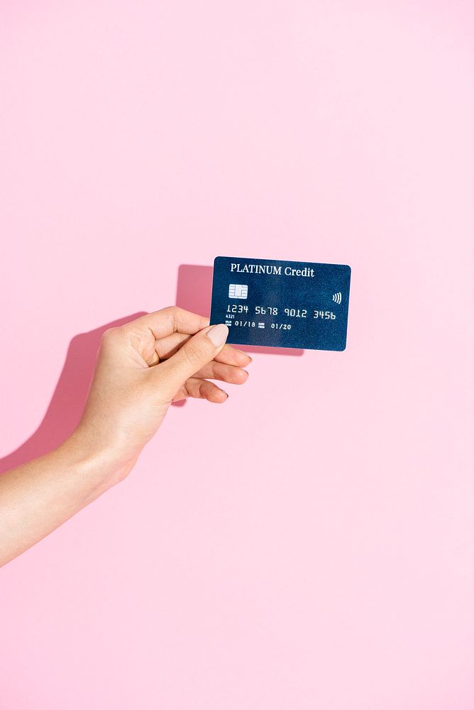 Woman holding a credit card against a pink background 