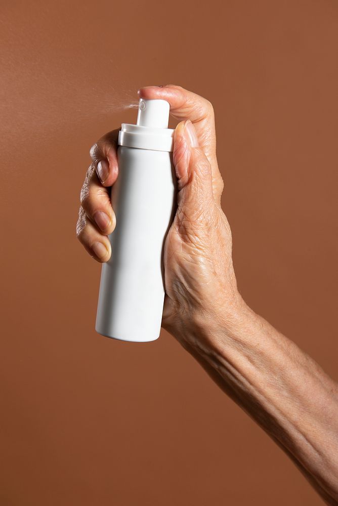 Hand holding a white aerosol spray bottle