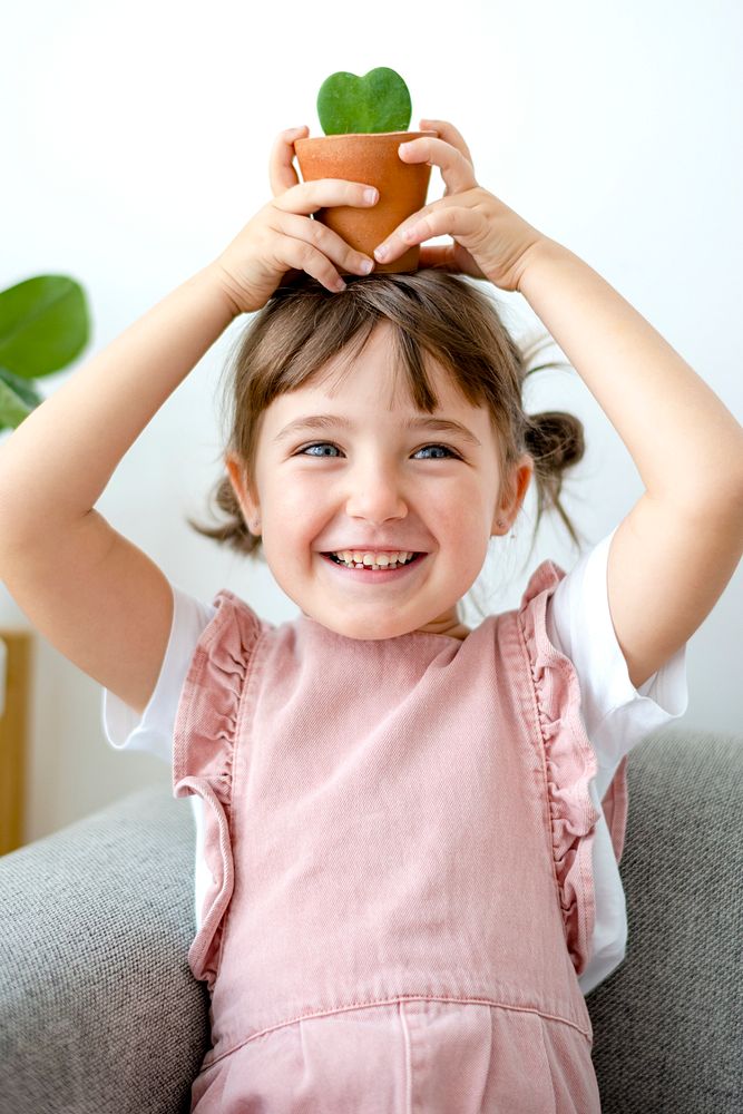 Cute girl kid holding potted plants at home