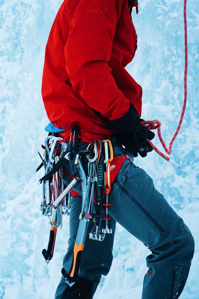 A person with ice climbing gear strapped to a harness on an ice wall. Original public domain image from Wikimedia Commons
