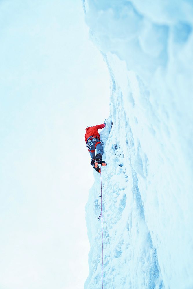 A person wearing a red shirt ice climbing, attached to a rope, at Bridal Veil Falls. Original public domain image from…