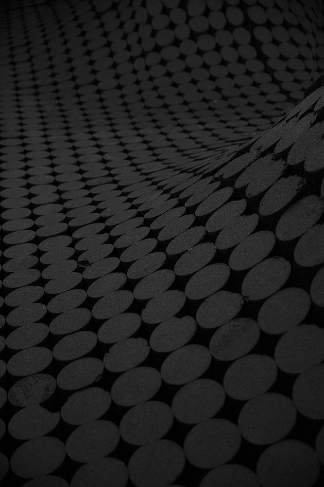 An undulating surface with a pattern of gray circles on a black texture. Original public domain image from Wikimedia Commons