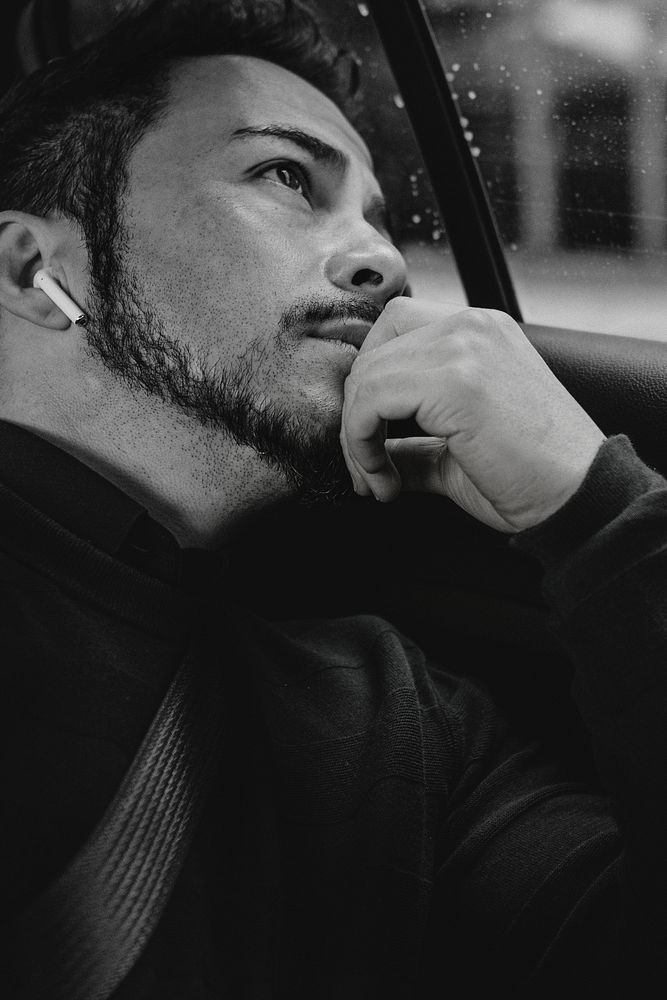 Man in a car with wireless earphones looking out the window