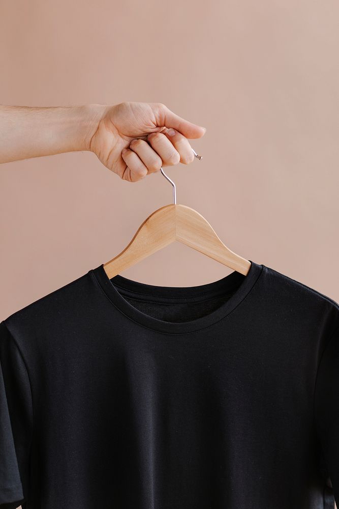 Hands holding a black t-shirt in a hanger