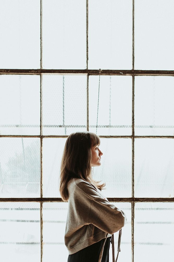 Brown hair woman standing by a window