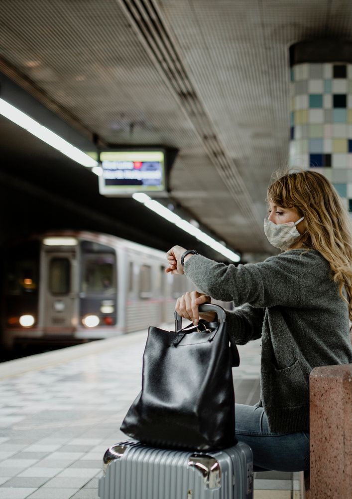 Woman looking at her watch while waiting for the train during the coronavirus pandemic 