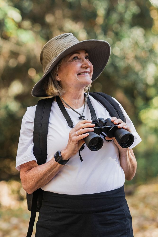 Active old woman using binoculars to see the beauty of nature