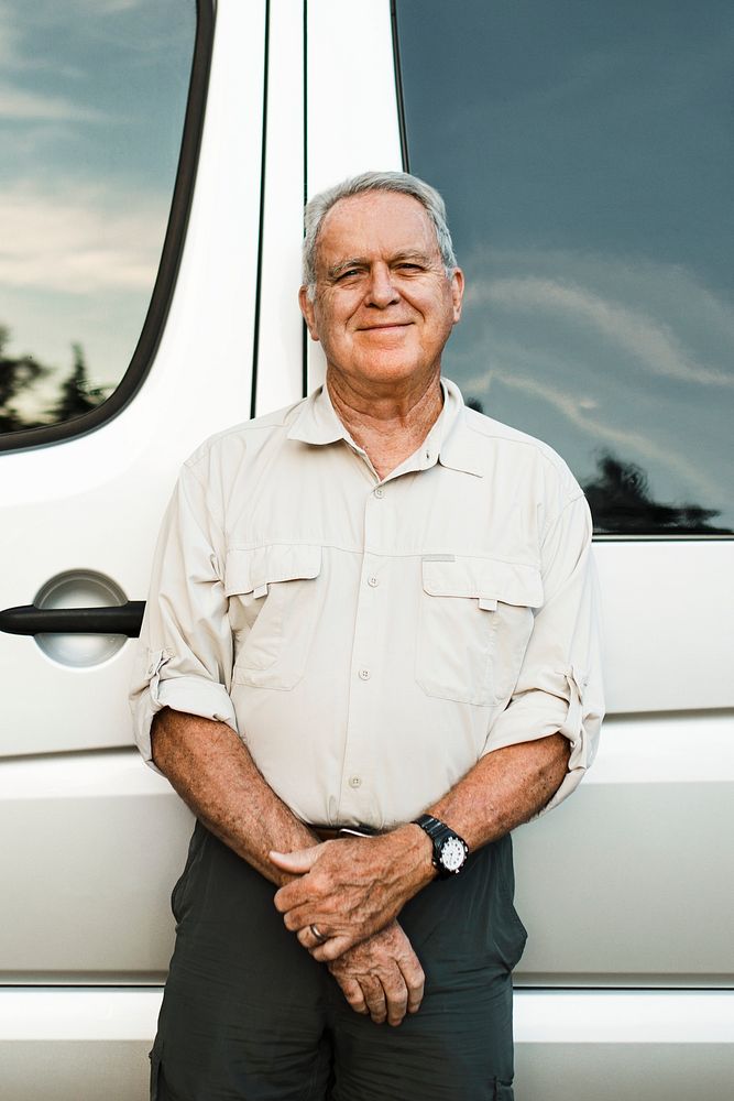 Senior man standing by the camper van