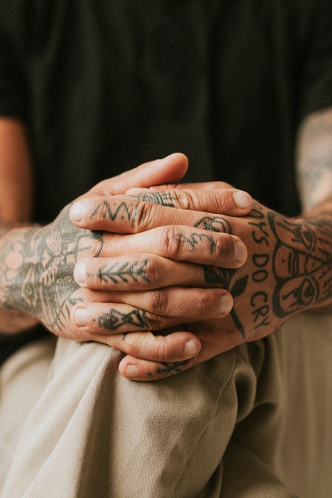 Tattooed man with hands clasping his knees. 2 OCTOBER 2020 - CHIPPENHAM, UK